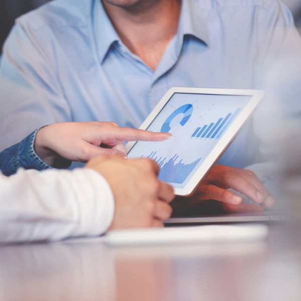 Hand pointing at graphs on tablet during meeting