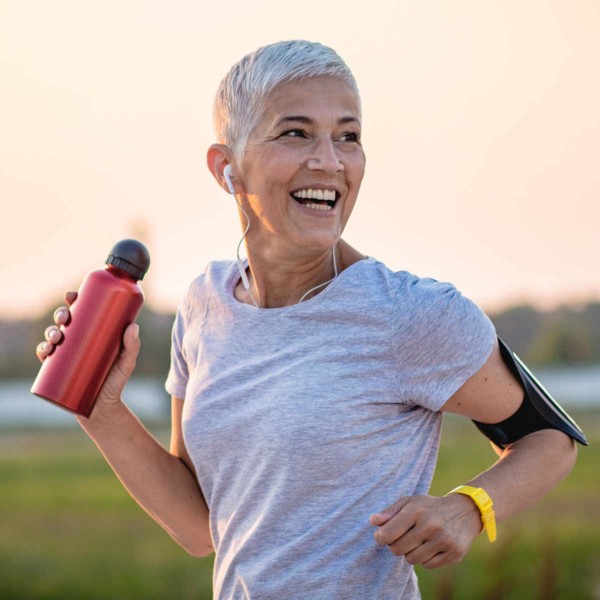 Image of someone running with a bottle of water in their hand and smiling.
