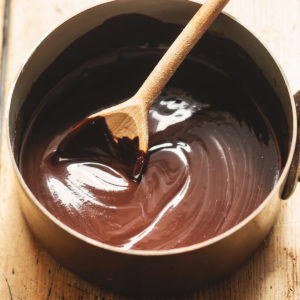 Stirring melted chocolate in bowl with a wooden spoon