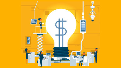 Image of a giant light bulb with a dollar sign being worked on by people in a lab.