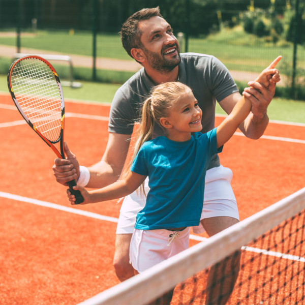 ad teaching his daughter how to play tennis