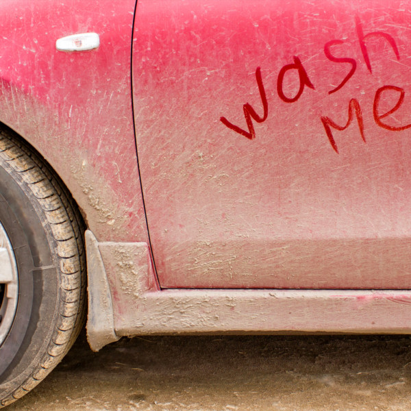 Car covered in dirt with “wash me” written in the dirt