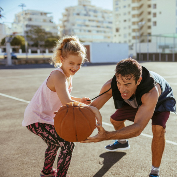 Image of father and daughter playing basketball together