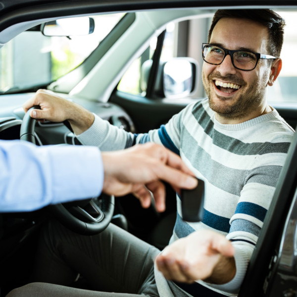 Man smiling while receiving keys to car