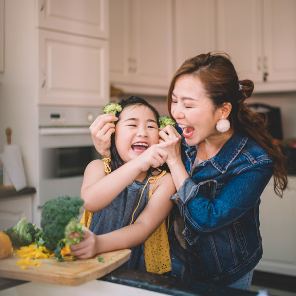 Mother and daughter eating broccoli in the kitchen
