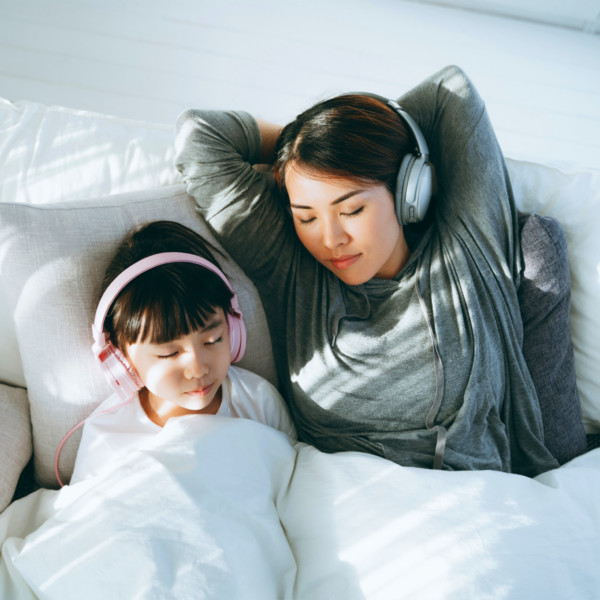 Image of a mother and daughter relaxing together with headphones on.