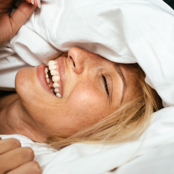 Woman smiling in bed under the covers