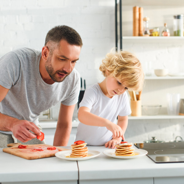 Image of father and son cooking pancakes in white kitchen