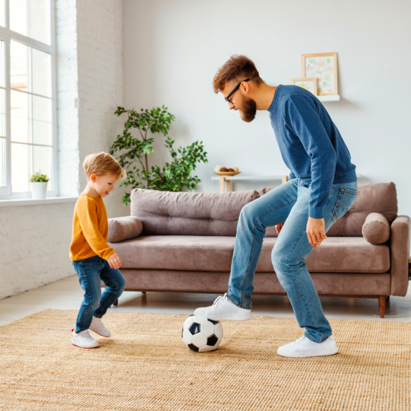 Image of father and son playing soccer in living room
