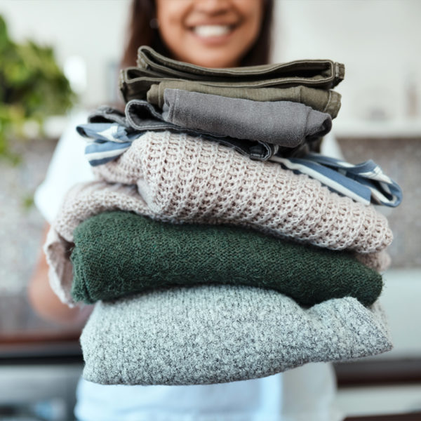 Woman holding stack of clothing for her capsule wardrobe