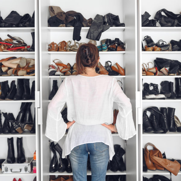 Woman standing in front of disorganized wardrobe in need of a capsule wardrobe